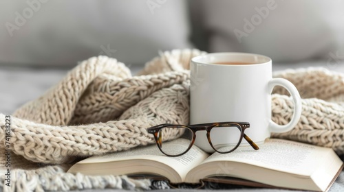 Cozy hygge home  beige sweater  tea or coffee mug  book  and glasses on gray bed