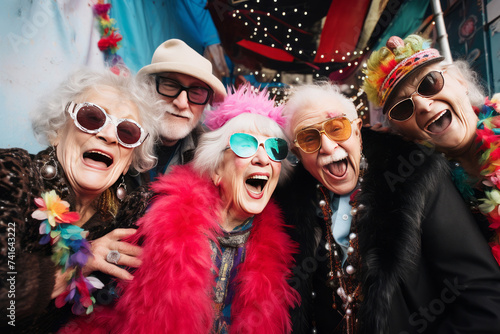 Joyful senior friends partying in colorful costumes with cheerful poses
