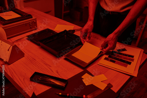 cropped shot of photographer skillfully prepares a film negative for development in darkroom photo