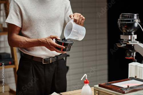 Tablou pe pânză cropped shot of african american photographer pouring chemical solution into fil