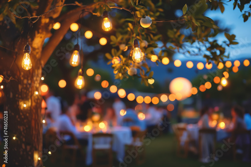 Close up of warm outdoor light bulbs with wedding reception blurred in background. photo