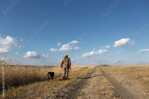 Mature man hunter with gun while walking on field with your dogs © Budjak Studio