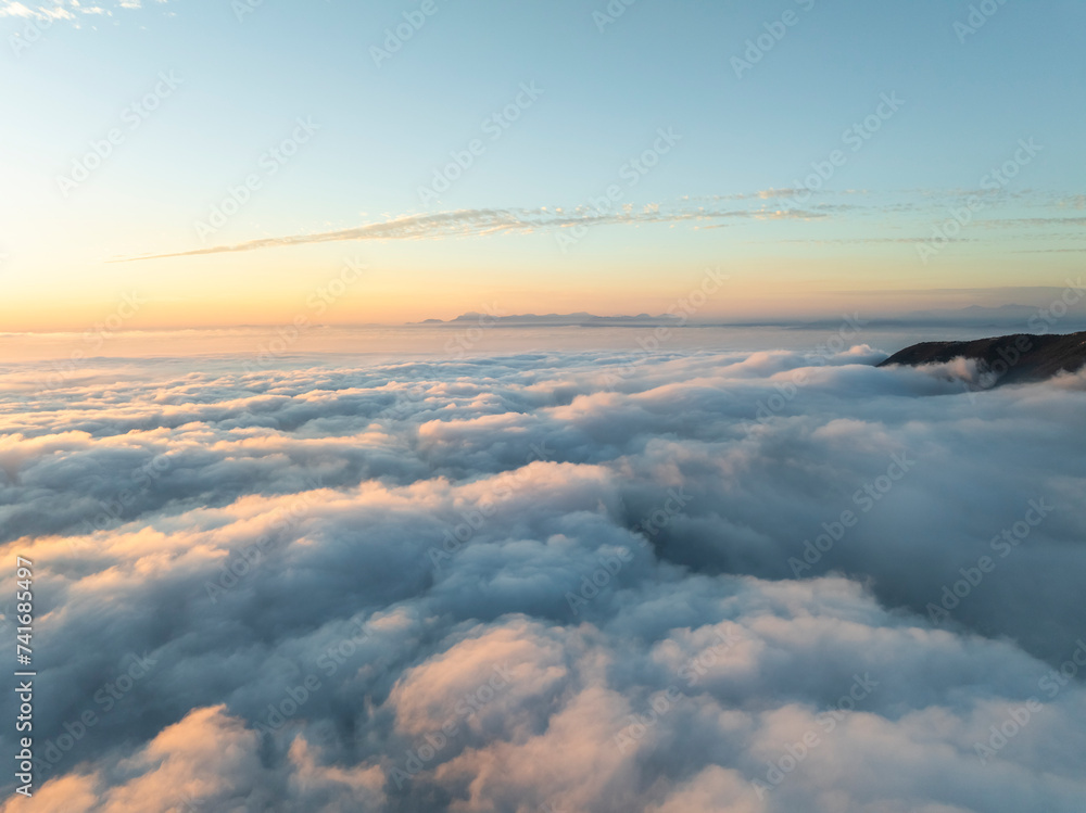 Aerial view of mountain range surrounded by low clouds at sunset and the Amalfi Coast in background as seen from the plane, Salerno, Campania, Italy. Aerial view of mountain range surrounded by low clouds at sunset and the Amalfi Coast in background as seen from the plane, Salerno, Campania, Italy.