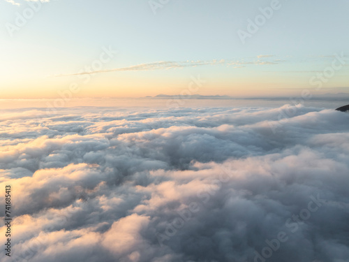 Aerial view of mountain range surrounded by low clouds at sunset and the Amalfi Coast in background as seen from the plane, Salerno, Campania, Italy. photo
