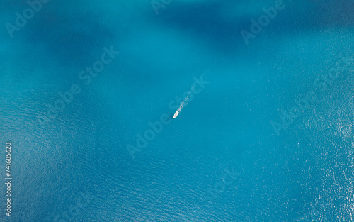 Aerial drone top-down view of a boat in clear blue water at the Eastern Peninsula coastline of Madeira island, Portugal. photo
