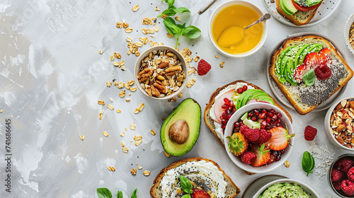 Healthy breakfast toasts with avocado, berries, cream cheese and seeds, bowls of granola, and honey on grey textured background. Flat lay composition with place for text. Balanced diet and clean eatin photo