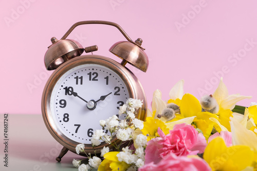 Alarm clock with spring flowers. Spring time, daylight savings concept, spring forward