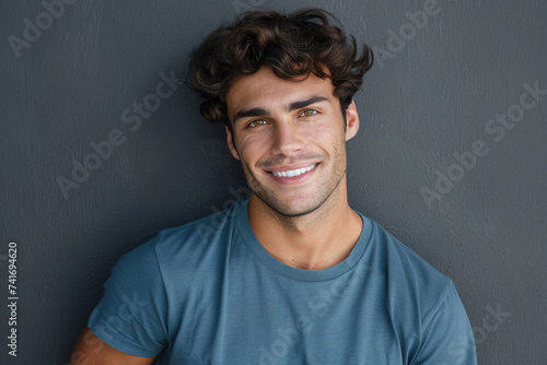 Close up portrait of young smiling handsome guy in blue t-shirt isolated on grey background