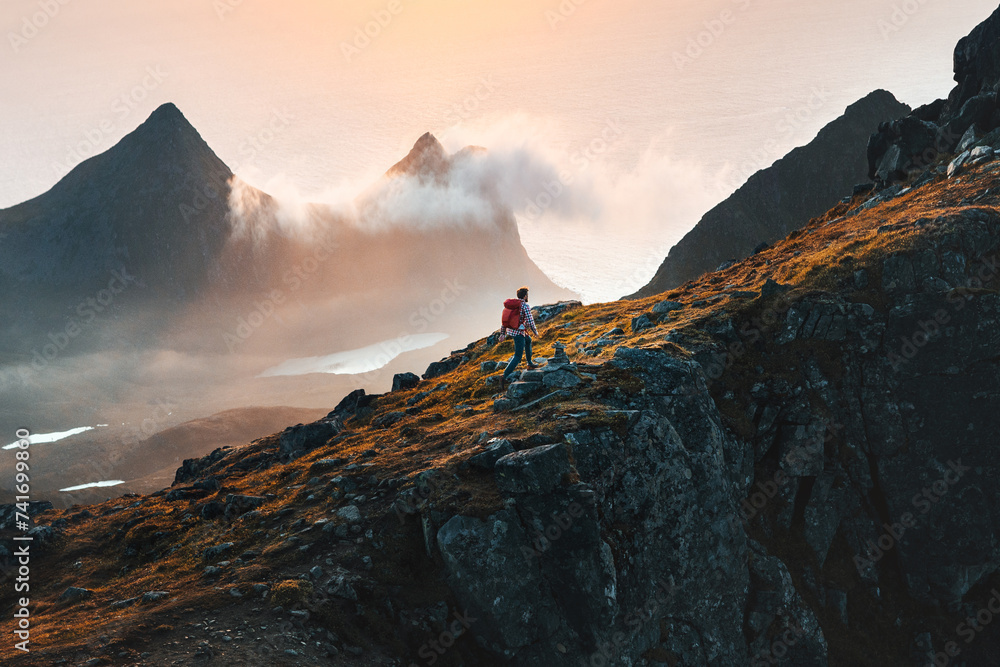 Man climbing mountains traveling in Norway tourist solo hiking in Lofoten islands outdoor traveler with backpack active healthy lifestyle adventure summer vacations - obrazy, fototapety, plakaty 
