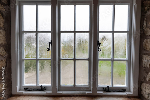Condensation on inside of single glazed windows in wooden frame in morning