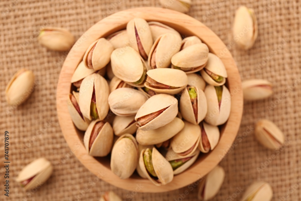 Tasty pistachios in bowl on burlap fabric, top view Tasty pistachios in bowl on burlap fabric, top view