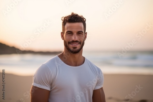 Portrait of handsome young man smiling on the beach at sunset.