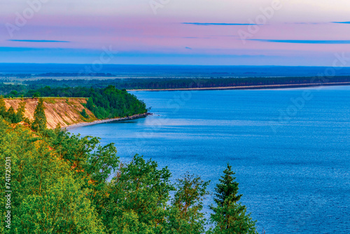 Seascape - the shore of Lake Onega in selective focus against the background of clouds at sunset.Karelian landscape.Nature, ecology, ecotourism.Forest lake. photo