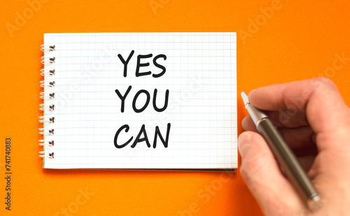 Motivational Yes you can symbol. Concept words Yes you can on beautiful white note. Beautiful orange background. Businessman hand. Business motivational and Yes you can concept. Copy space