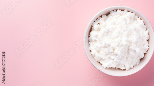 Cottage cheese in a bowl on pink background with copy space