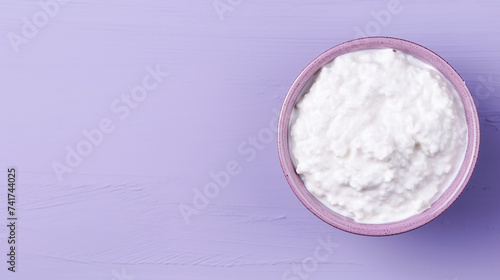 Cottage cheese in a bowl on purple background with copy space
