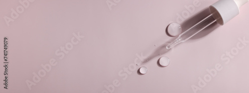 dense liquid  dripping  flowing  skincare concept. Cosmetic pipette with drops of serum  vitamin or oil on pink background. copy space