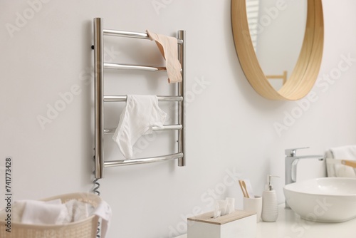 Heated towel rail with underwear on white wall in bathroom photo