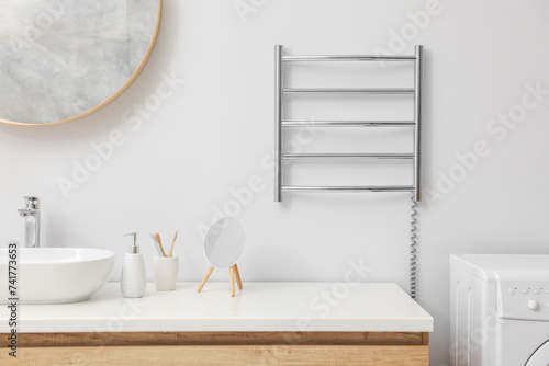 Heated towel rail on white wall in bathroom photo