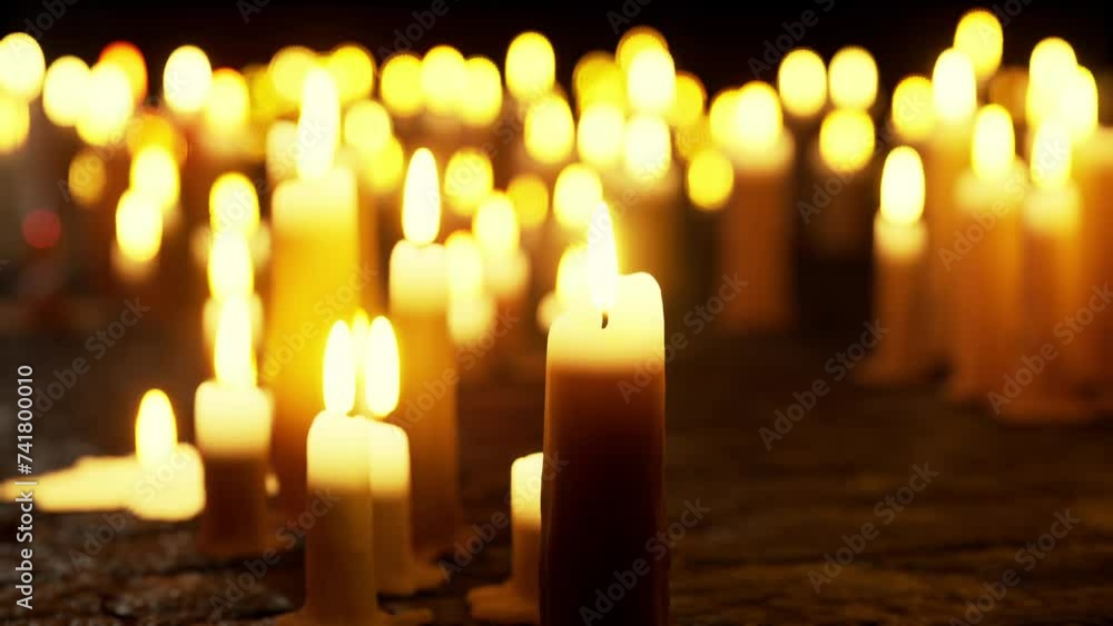 Multiple rows of candles emit warm light, illuminating a dimly lit room. Multiple rows of candles emit warm light, illuminating a dimly lit room.