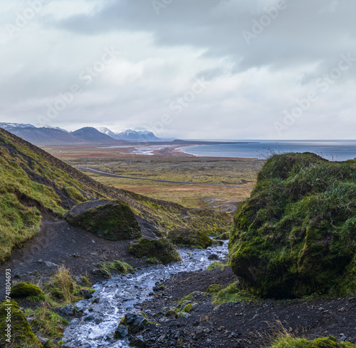 View during auto trip in West Iceland highlands, Snaefellsnes peninsula, Snaefellsjokull National Park. Spectacular volcanic tundra view from Raudfeldsgja Gorge along stream to ocean coast.