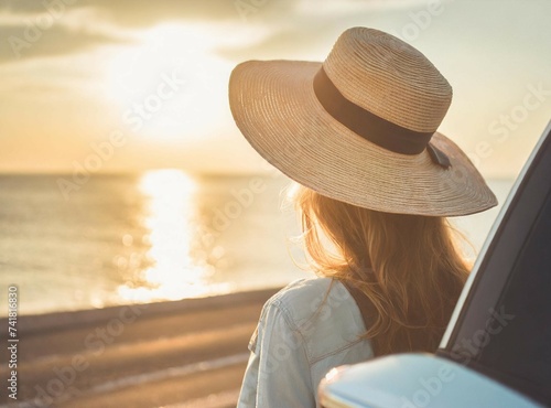 Young woman traveler in a hat standing near her car during summer holiday on the sea.