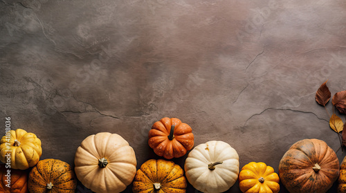 A group of pumpkins with dried autumn leaves and twig, on a vivid brown color stone