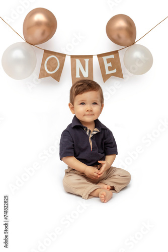 Bebé de un año sentado delante de un fondo blanco, celebrando su primer año con globos photo