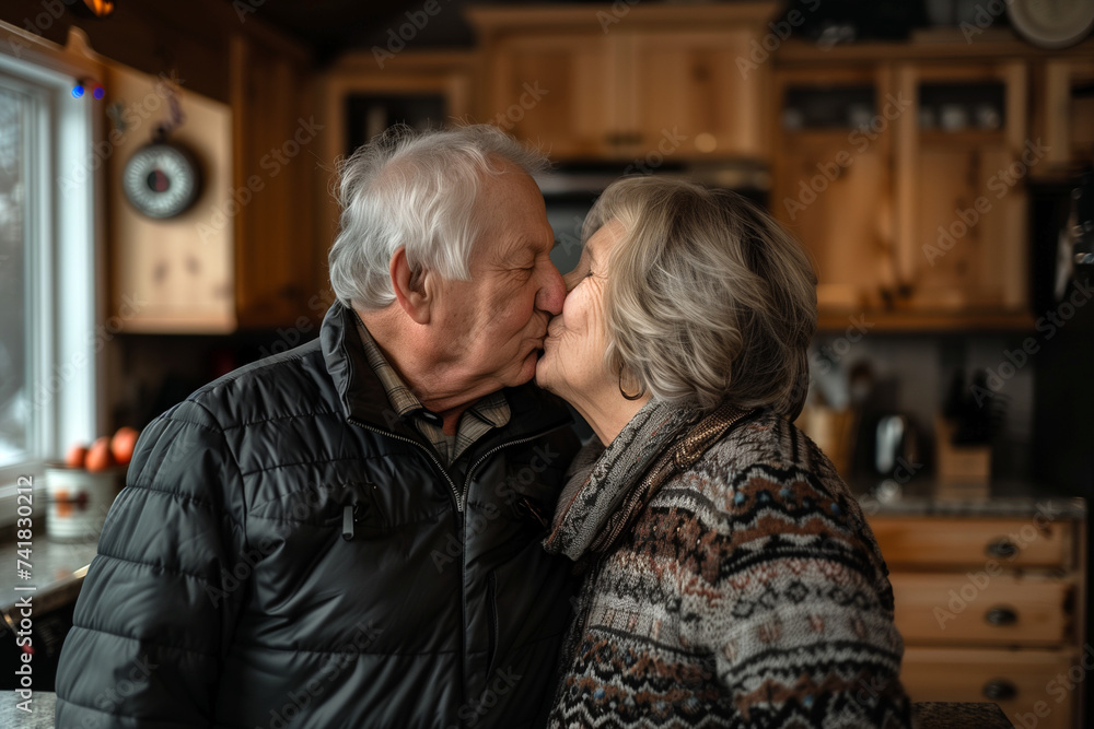 Senior couple kissing each other while standing by kitchen island at home Senior couple kissing each other while standing by kitchen island at home