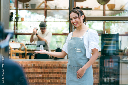 Hand of coffee shop staff woman wearing apron turning open sign board on glass door in modern cafe, morning of hotel service or restaurant retail store, small business owner in food and drink concept photo