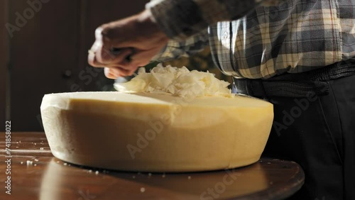 whole piece of parmesan cheese. Italian farmer pealing flakes out of cheese. Typical and traditional italian way of cutting thw parmesan wheel. photo