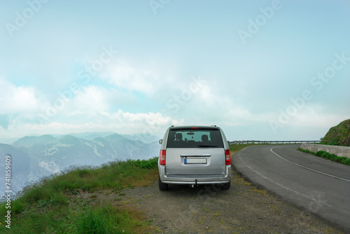 Traveling by car along mountain roads. The car is standing on the edge of a cliff. Magnificent views of the landscape, sky, mountain peaks. The concept of safety and insurance when traveling by car.