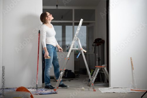 Young happy woman paints her apartment