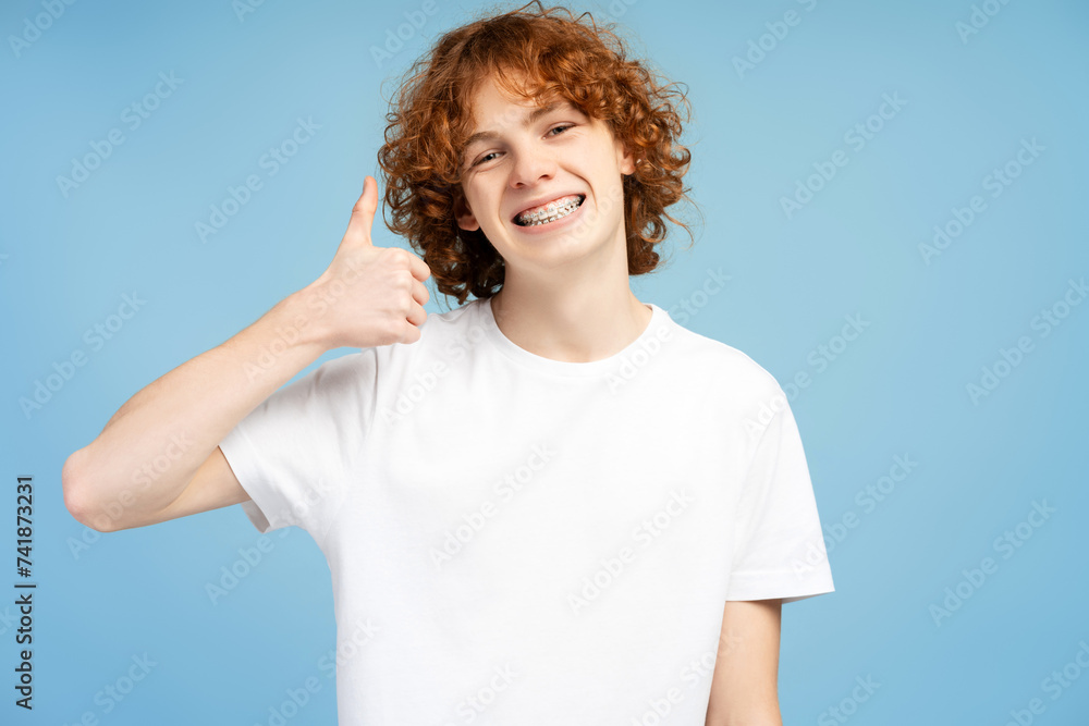 Cropped portrait of happy excited teen man with braces on teeth showing thumb up Cropped portrait of happy excited teen man with braces on teeth showing thumb up