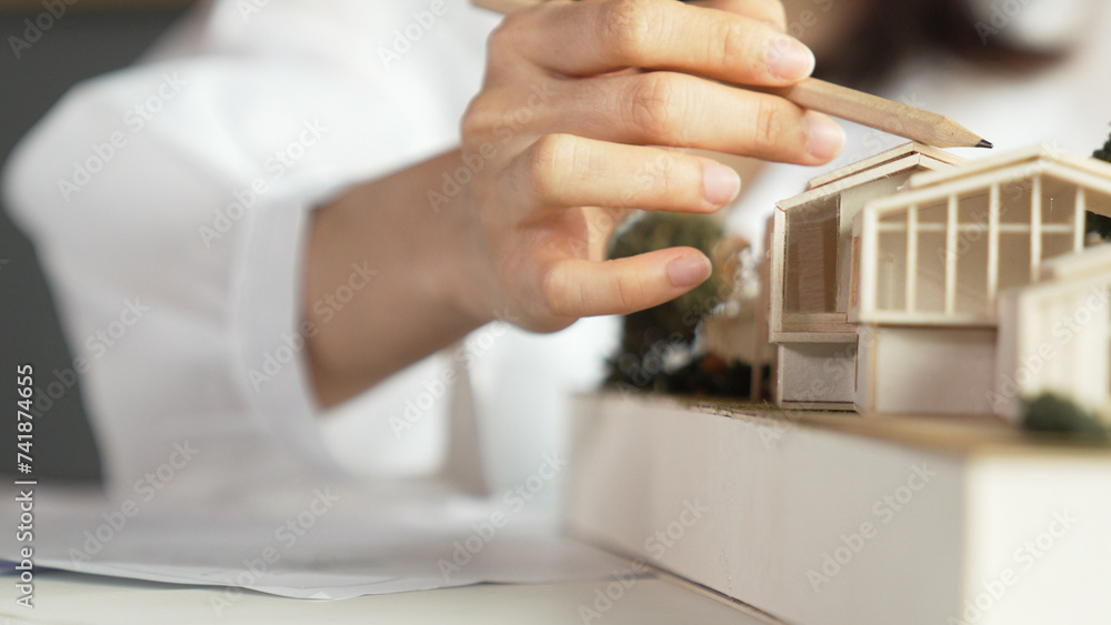 Closeup of young beautiful architect engineer measure house by using pencil. Interior designer pointing pencil to design house structure. Business design concept. Blurring background. Manipulator.