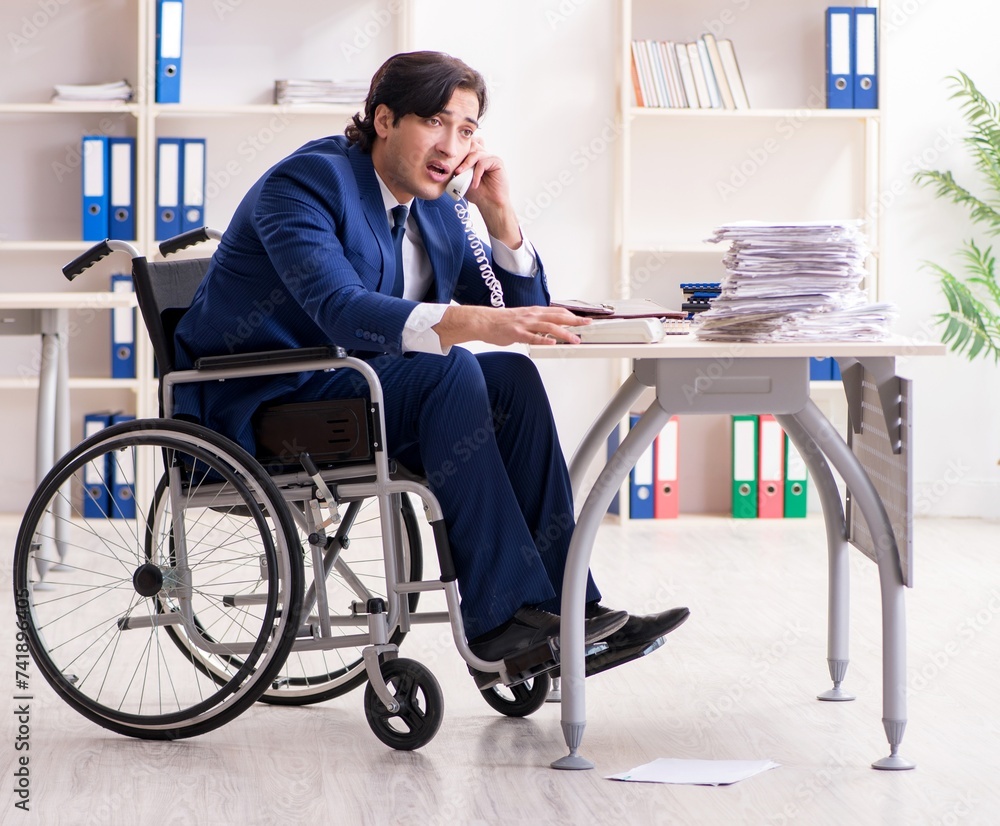 Young male employee in wheelchair working in the office Young male employee in wheelchair working in the office