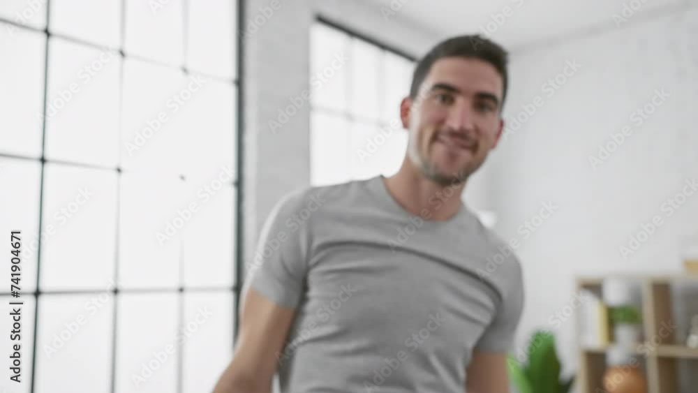 Handsome hispanic man smiling in a stylish modern living room with large windows and minimalist decor Handsome hispanic man smiling in a stylish modern living room with large windows and minimalist decor