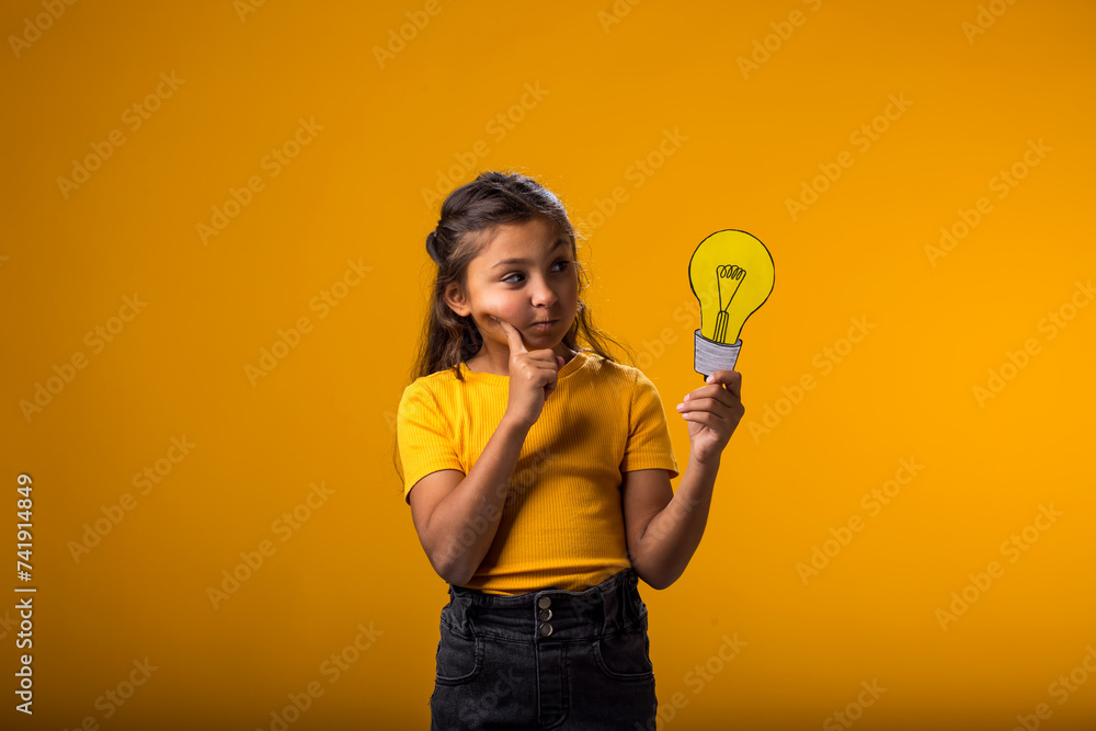Thoughtful child girl holding paper bulb. Success, motivation, winner, genius, idea concept Thoughtful child girl holding paper bulb. Success, motivation, winner, genius, idea concept