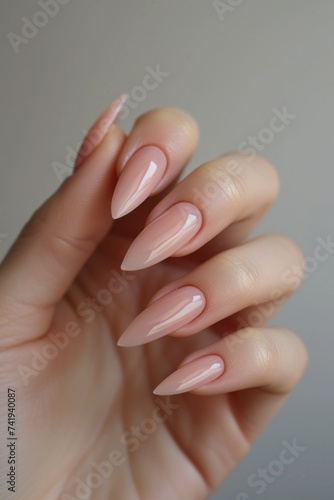 A close-up of a womans hand elegantly displaying a professionally manicured manicure in a neutral tone. The nails are neatly shaped and polished, enhancing the overall appearance of the hand