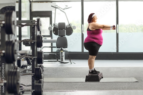 Woman standing on a stepper and exercising with dumbbells