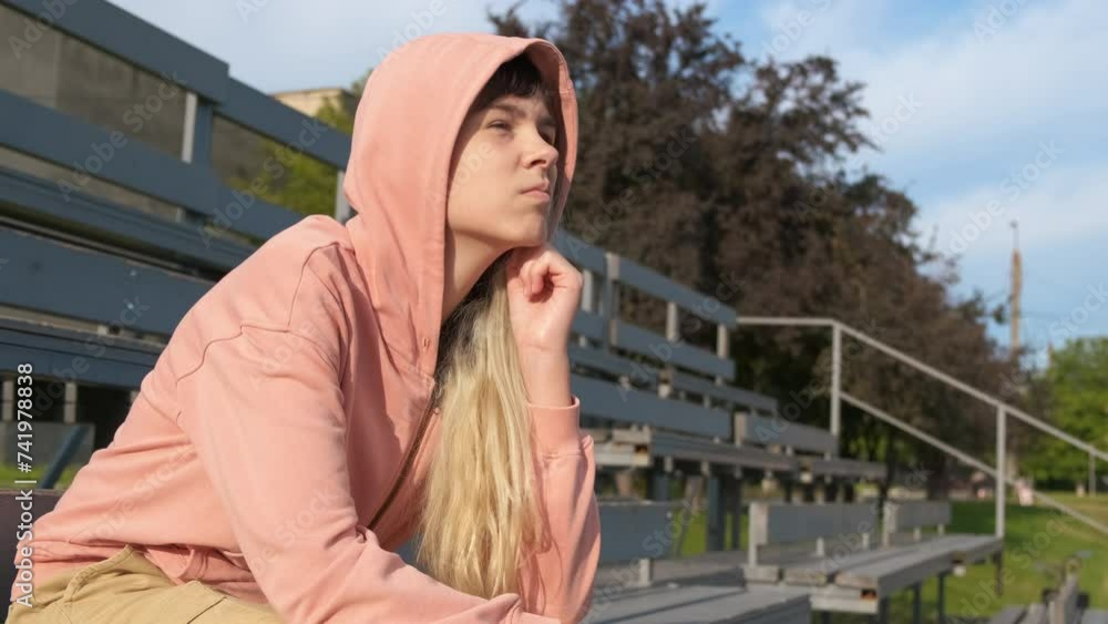 Depressed teen on sportground. A view of depressed young girl sitting in loneliness on stadium during day time. Depressed teen on sportground. A view of depressed young girl sitting in loneliness on stadium during day time.