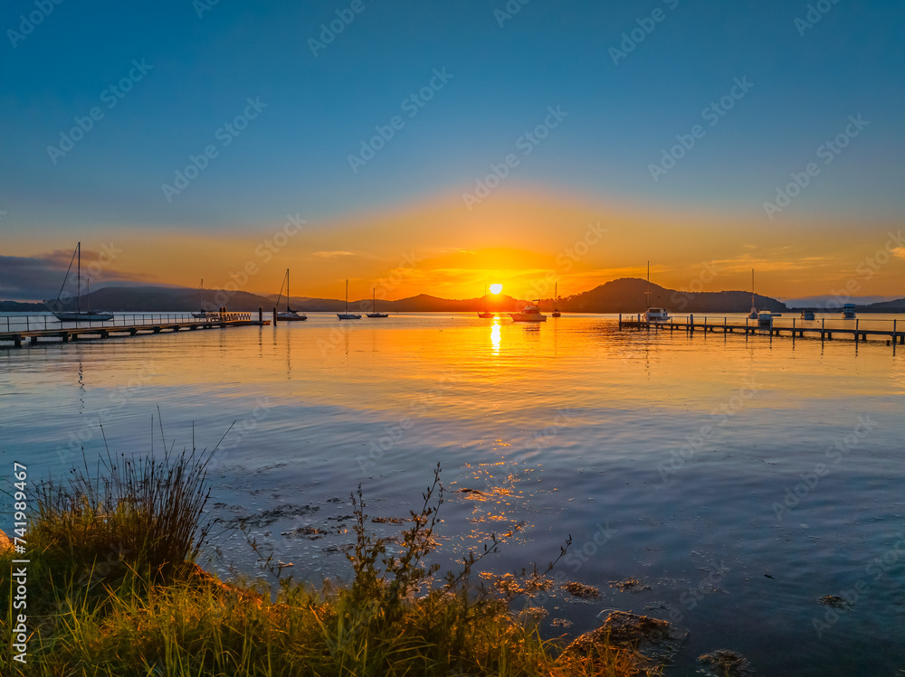 Sunrise over the calm water with boats and reflections