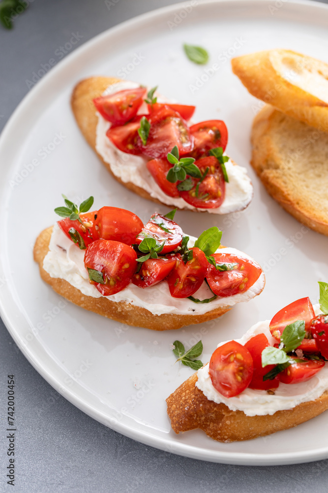 Making tomato basil crostini or bruschetta with toasted baguette