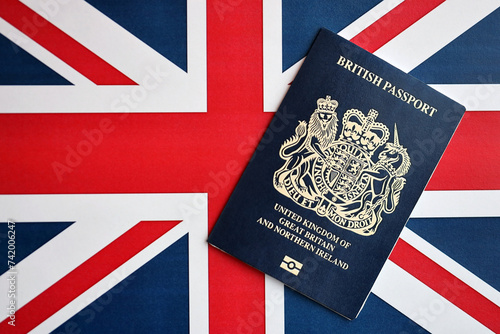 Blue British passport on national flag background close up. Tourism and citizenship concept photo