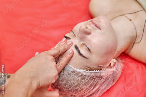 Female therapist doing facial massage with hands