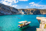 Boat on azure sea in beautiful Firopotamos bay, Milos island, Cyclades, Greece