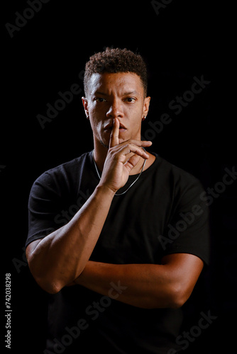 Obraz na płótnie Low key portrait of young African man making silence gesture w salonie
