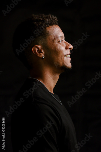 Low key portrait of young African man in profile smiling