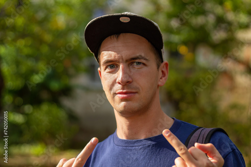 Obscene gesture. Young man in baseball cap and T-shirt shows the middle finger with both hands. Young man giving obscene gesture photo