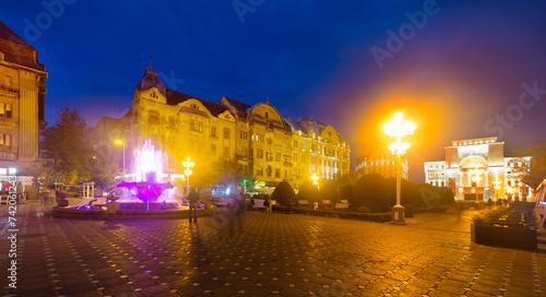 Night view of Victoriei Square with colored fountain and National Theatre and Opera, Timisoara
